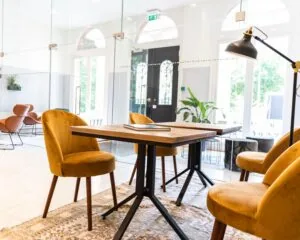 Moderne, lichte kantoorruimte met gele fluwelen stoelen, houten tafel en glazen wanden aan het Westplein 12-14 in Rotterdam.