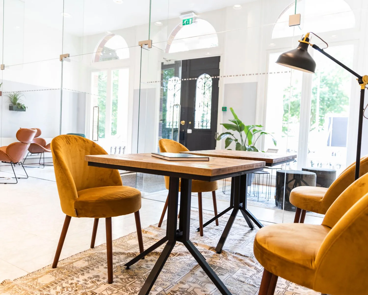 Moderne, lichte kantoorruimte met gele fluwelen stoelen, houten tafel en glazen wanden aan het Westplein 12-14 in Rotterdam.