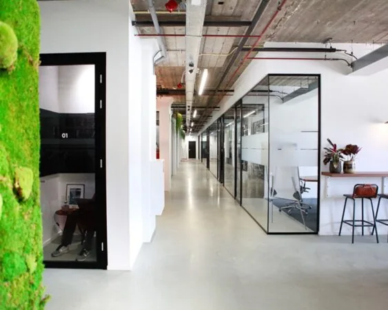 Moderne kantoorruimte aan de Wibautstraat 135-139 in Amsterdam met glazen wanden, industriële plafonds en een groene moswand.