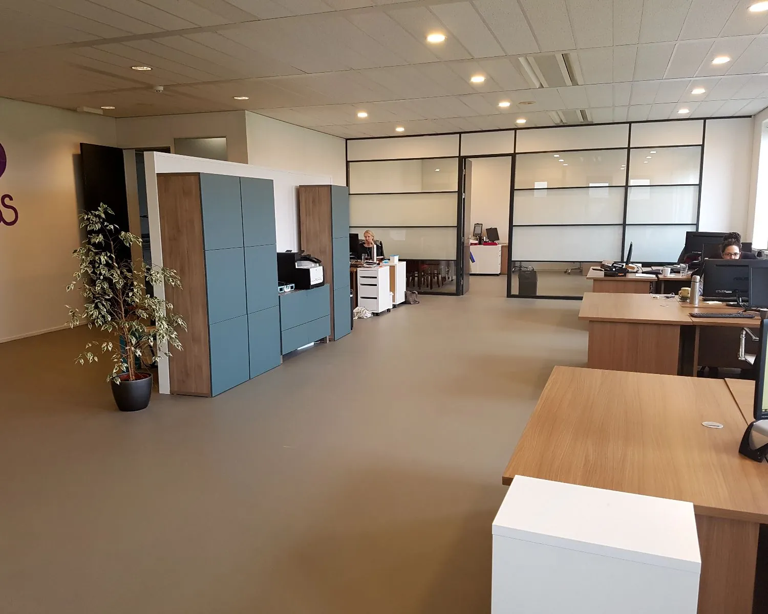 Moderne kantoorruimte met houten bureaus, glazen scheidingswanden en werkplekken aan de Zekeringstraat 17 in Amsterdam.