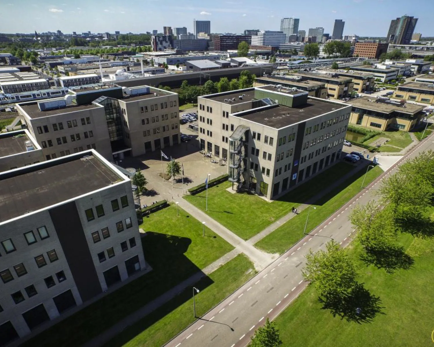 Luchtfoto van moderne kantoorgebouwen aan de Zekeringstraat 17 in Amsterdam met groene omgeving en stadszicht op de achtergrond.