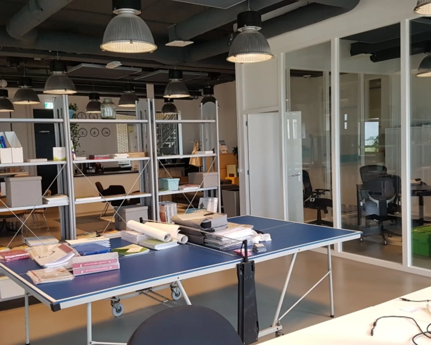 Moderne kantoorruimte in Amsterdam met glazen vergaderruimtes, open werkplekken en een tafeltennistafel als werktafel.