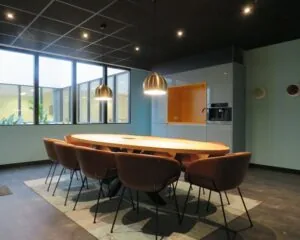 Moderne vergaderruimte met ovale houten tafel, acht stoelen en ingebouwde pantry in een kantoor aan de Zekeringstraat 43 in Amsterdam.