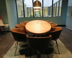 Moderne vergaderruimte met ovale houten tafel, omringd door leren stoelen en grote ramen aan de Zekeringstraat 43 in Amsterdam.