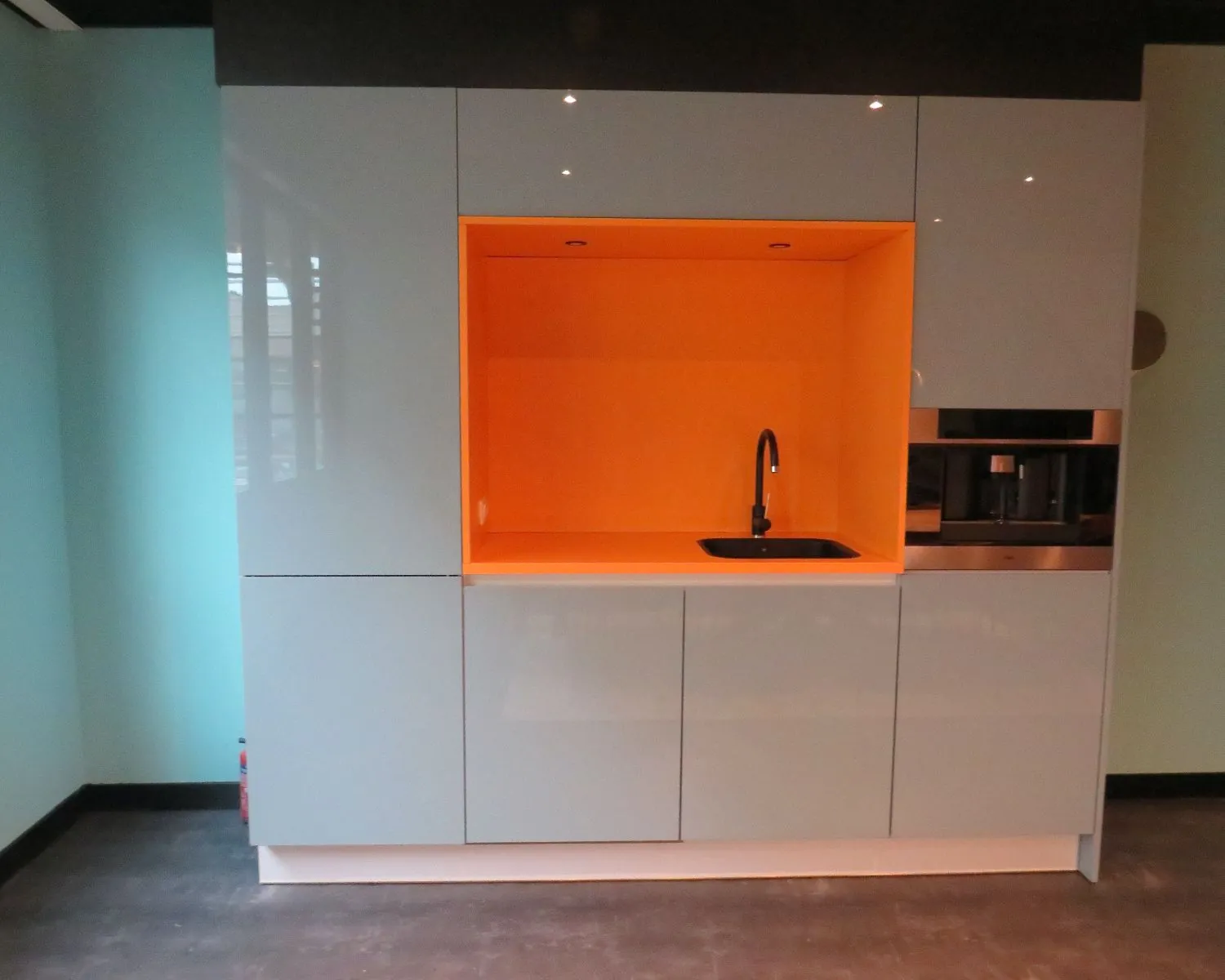 Moderne kantoorpantry met oranje nis, ingebouwde spoelbak en koffiemachine aan de Zekeringstraat 43 in Amsterdam.