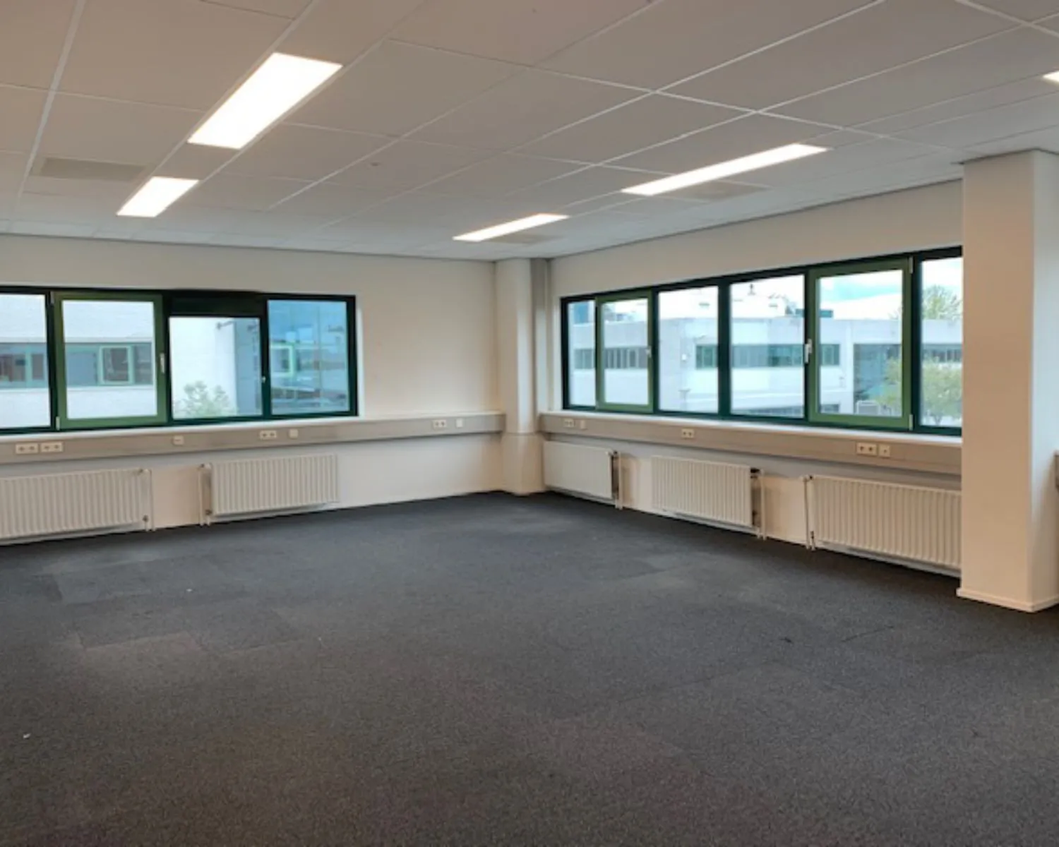 Lichte, lege kantoorruimte met tapijtvloer en grote ramen aan de Zekeringstraat 43 in Amsterdam.