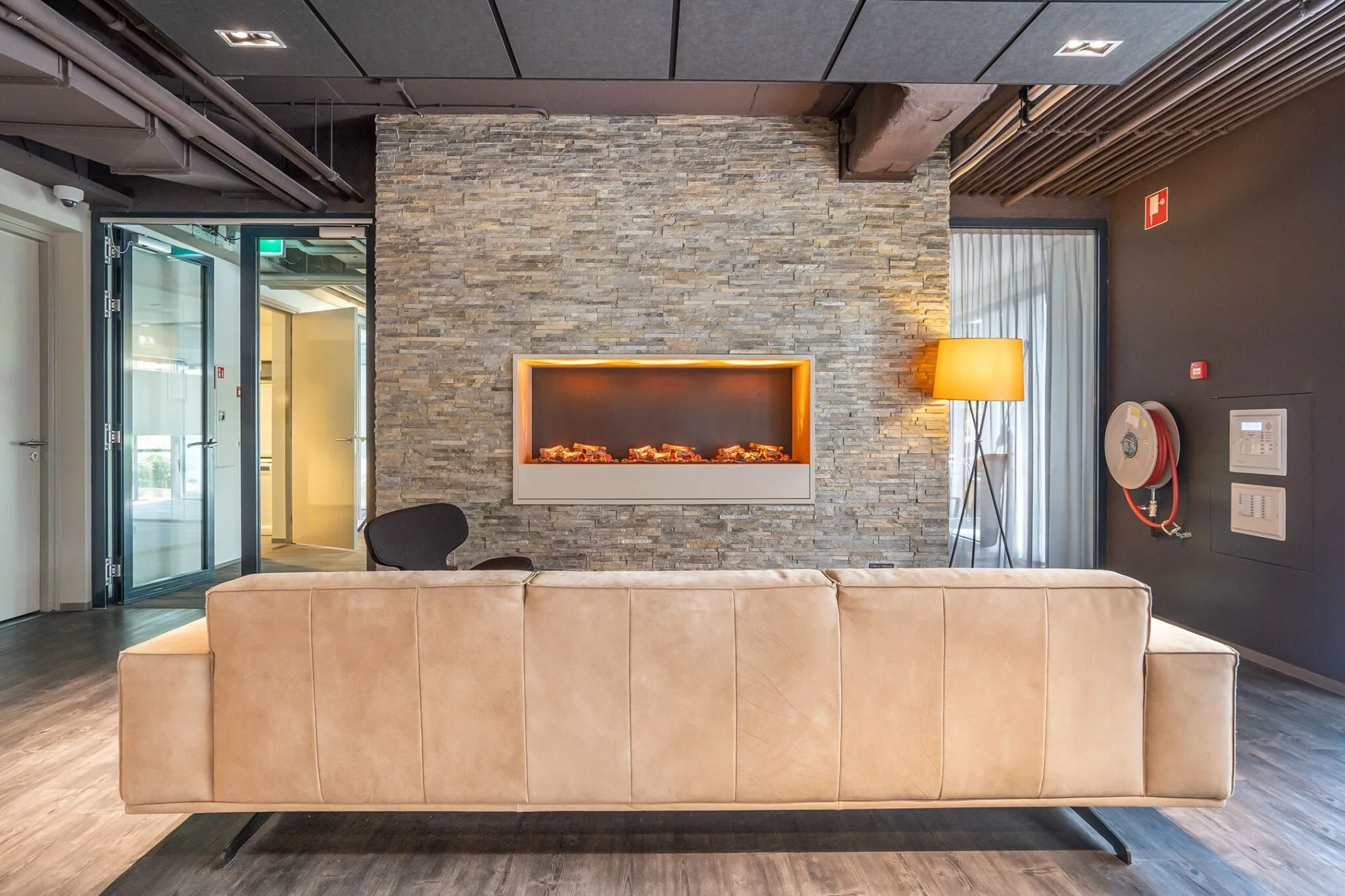 Moderne loungehoek in Kanaalpark 140 met beige bank, elektrische haard en sfeerverlichting.