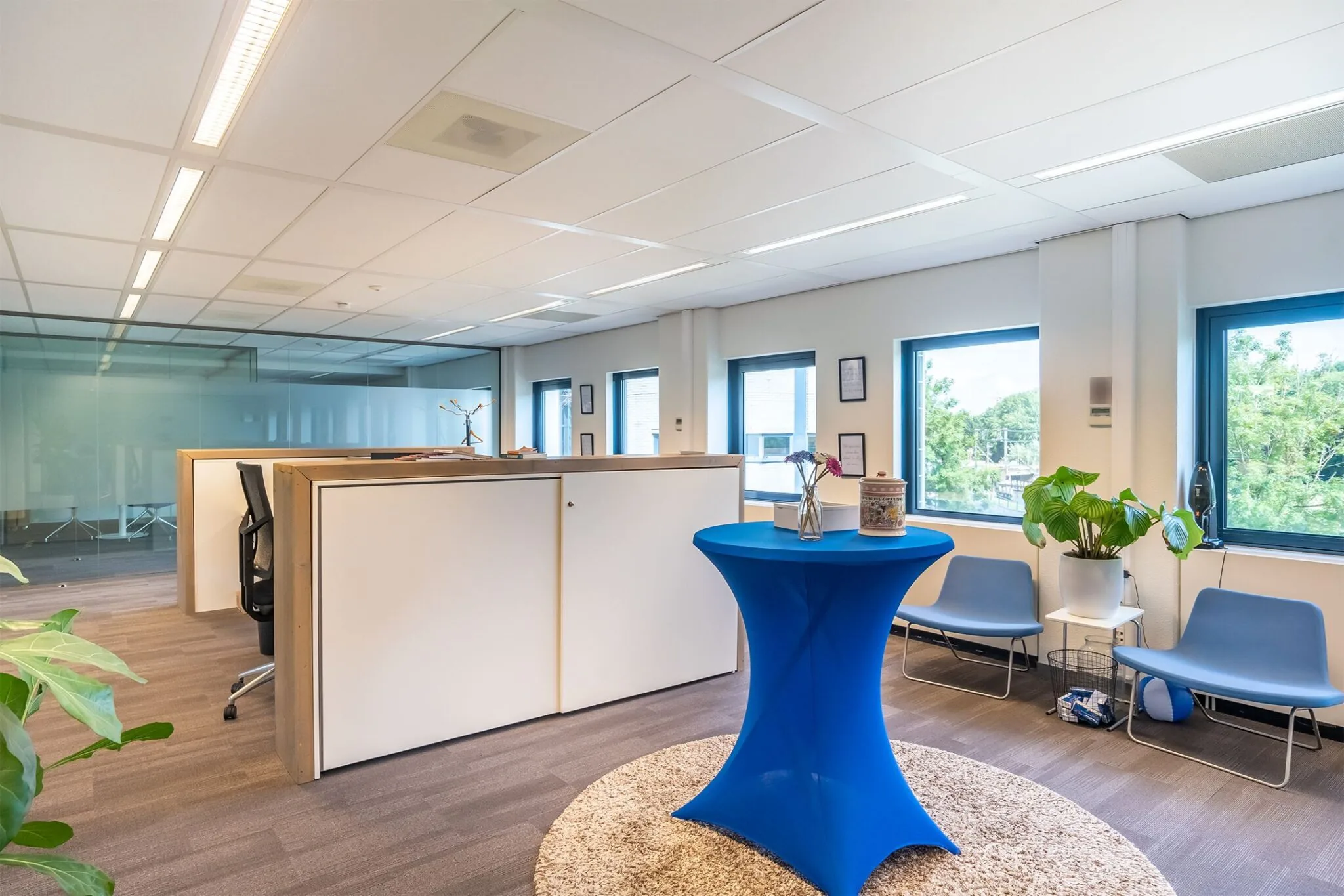 Moderne kantoorruimte in Kanaalpark 140 met zitgedeelte, blauwe statafel en veel natuurlijk licht.