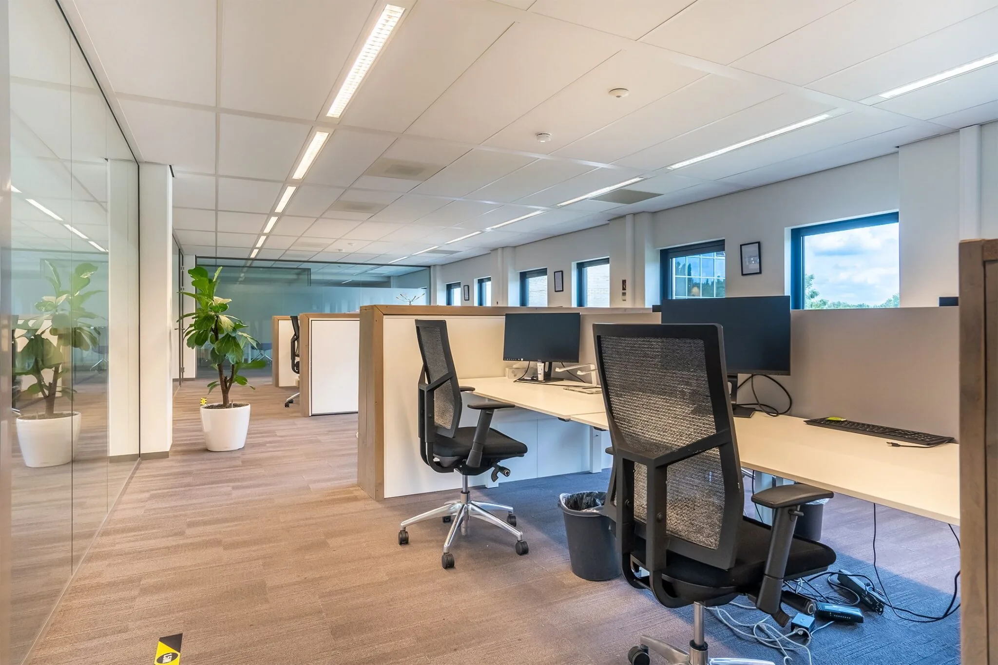 Moderne en lichte kantooruimte in Kanaalpark 140 met werkplekken, bureaustoelen en planten.