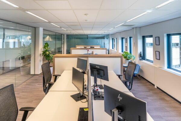 Modern kantoorinterieur in Kanaalpark 140 met werkplekken, bureaustoelen en computers langs grote ramen.