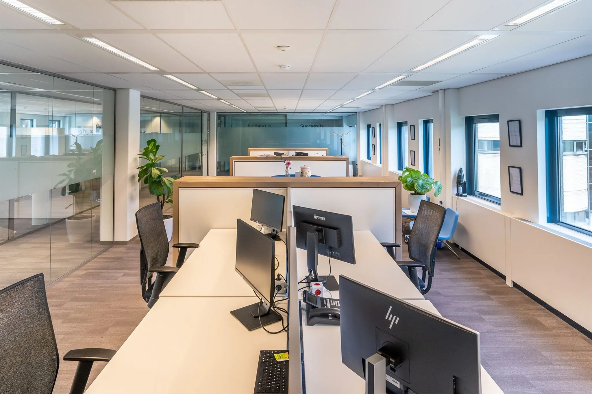 Modern kantoorinterieur in Kanaalpark 140 met werkplekken, bureaustoelen en computers langs grote ramen.