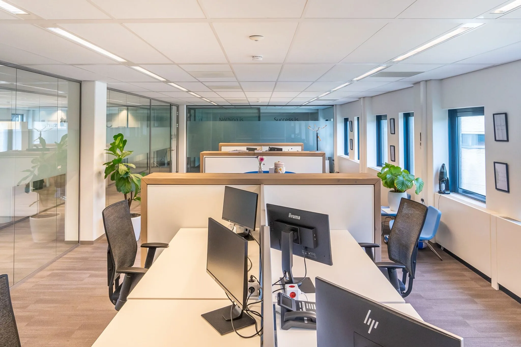 Modern kantoorinterieur met werkplekken, bureaustoelen, computerschermen en kamerplanten bij Kanaalpark 140.
