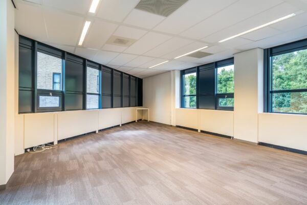 Leeg kantoor met grote ramen en beige tapijtvloer in het gebouw Kanaalpark 140.