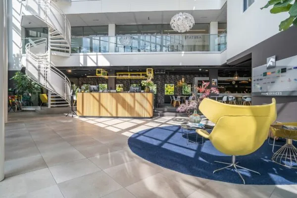 Moderne en lichte ontvangsthal van Kanaalpark 140 met designmeubilair, een houten balie en een opvallende wenteltrap.