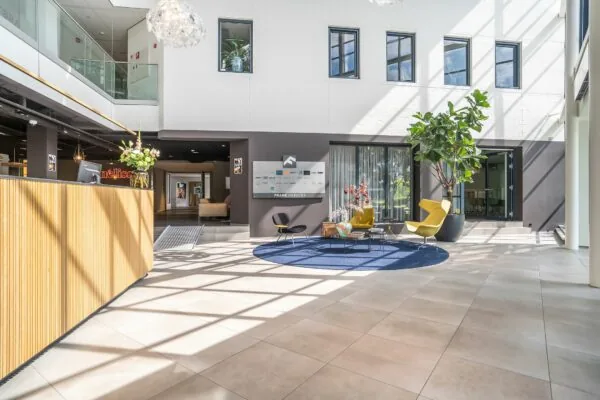 Moderne en lichte ontvangsthal van Kanaalpark 140 met zitgedeelte, balie en grote raampartijen.