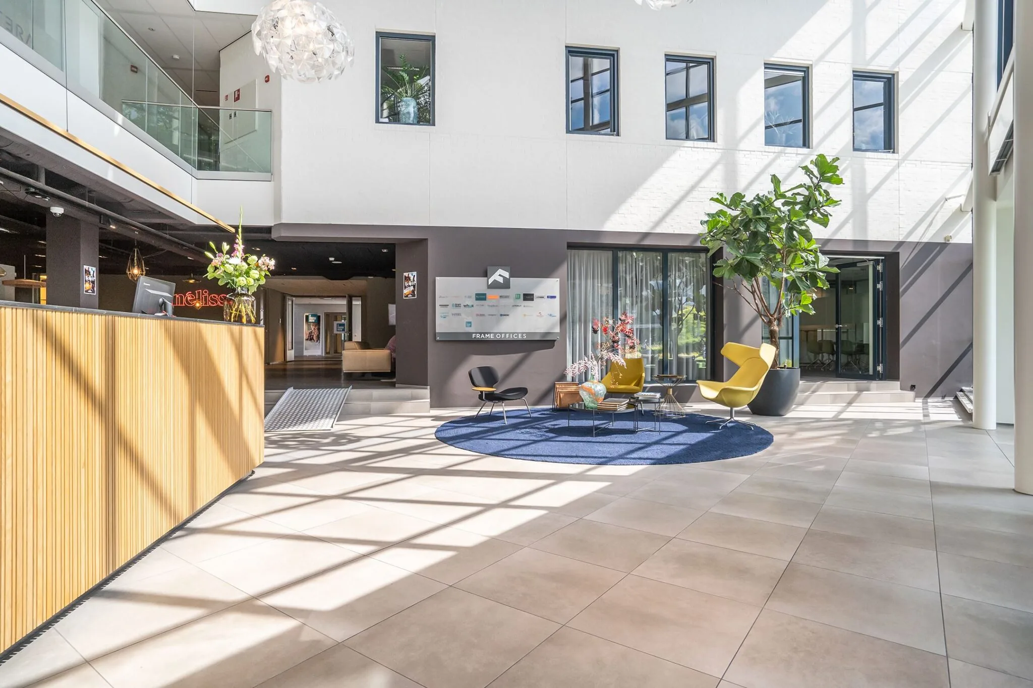 Moderne en lichte ontvangsthal van Kanaalpark 140 met zitgedeelte, balie en grote raampartijen.