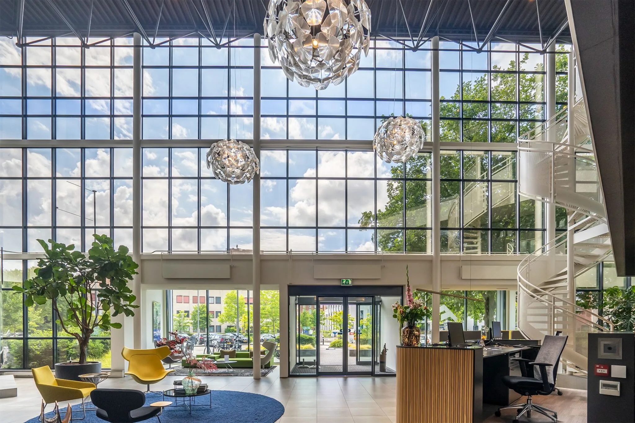 Moderne en lichte entreehal van Kanaalpark 140 met hoge ramen, een ronde trap, designmeubels en een receptiebalie.