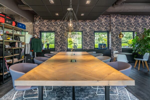 Moderne vergaderruimte in Kanaalpark 140 met een lange houten tafel, designstoelen en decoratieve verlichting.