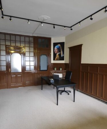 Stijlvol ingerichte kantoorruimte met zwart bureau en schilderij aan de muur, gelegen aan de Aelberchtskolk 45b1 in Rotterdam.