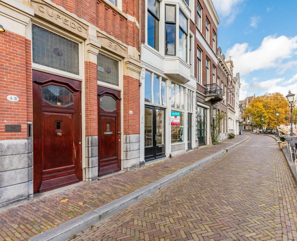 Gevel van het kantoorpand aan de Aelbertskolk 45b1 in Rotterdam met te huur-bord en uitzicht op een rustige, geplaveide straat.