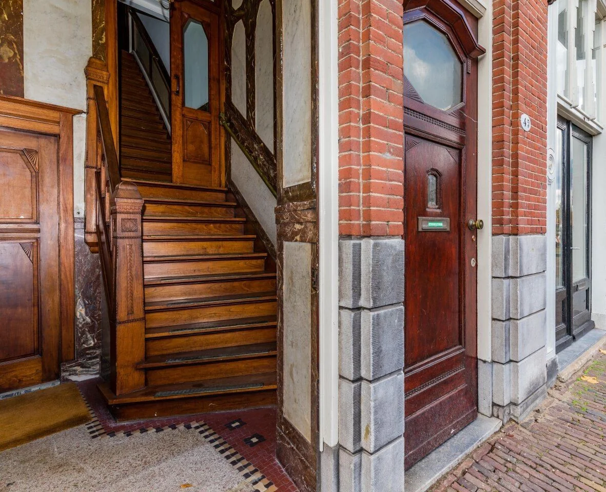 Entree van kantoorruimte aan de Aelberchtskolk 45b1 in Rotterdam met houten trap en klassieke voordeur.