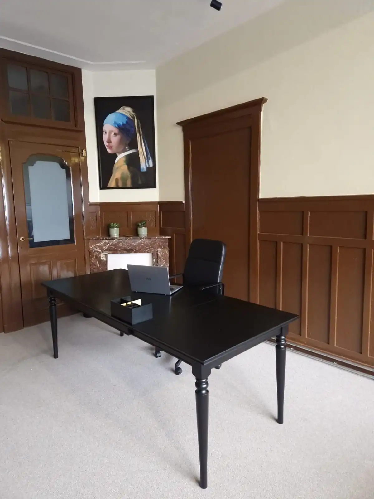 Moderne kantoorruimte aan de Aelberchtskolk 45b1 in Rotterdam met zwart bureau, bureaustoel en schilderij van het Meisje met de parel aan de muur.