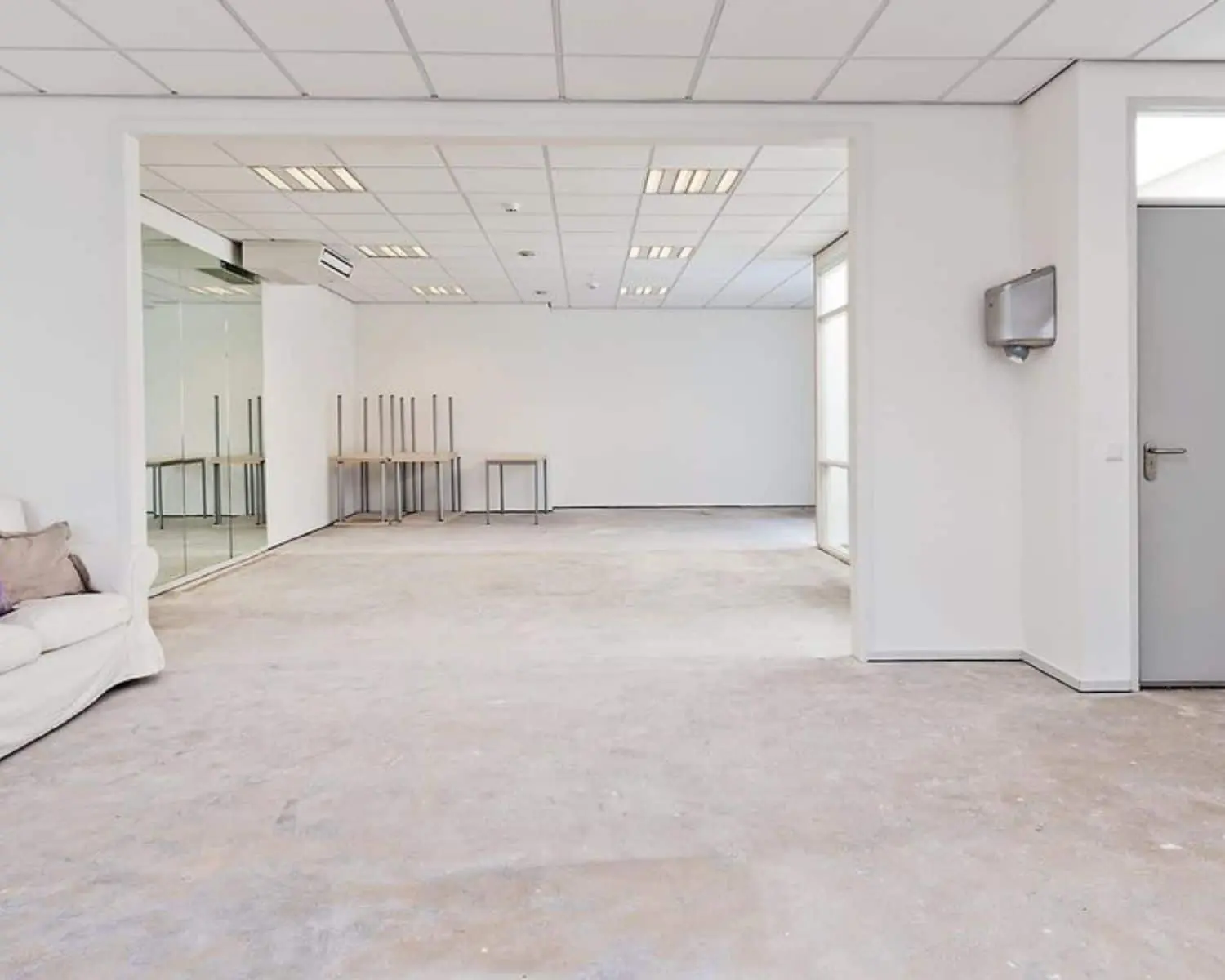 Lege, lichte kantoorruimte aan de Amstel 62 in Amsterdam met systeemplafond en stapelbare tafels.