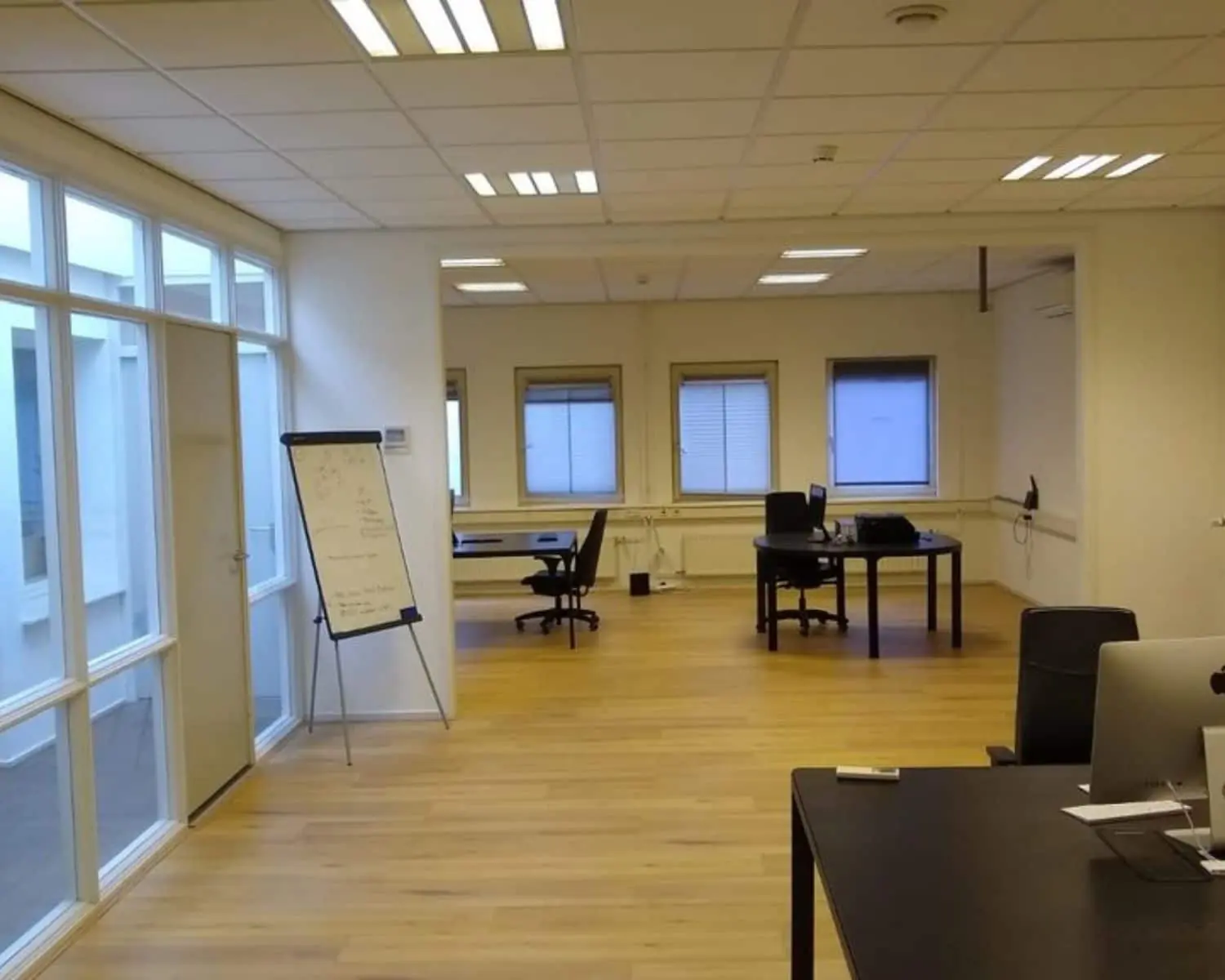 Moderne, lichte kantoorruimte met houten vloer en meerdere werkplekken aan de Amstel 62 in Amsterdam.