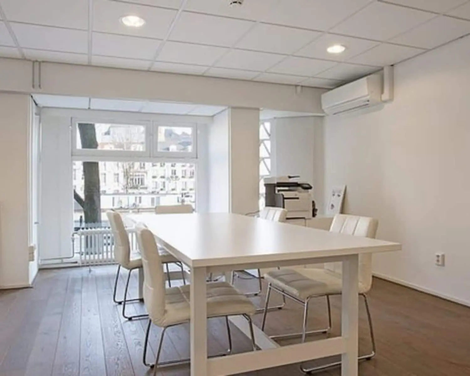 Moderne vergaderruimte met witte tafel en stoelen in een kantoor aan de Amstel 62 in Amsterdam.