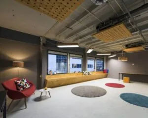 Moderne en kleurrijke kantoorruimte aan de Hogehilweg 20 in Amsterdam met zithoeken, ronde vloerkleden en grote ramen.