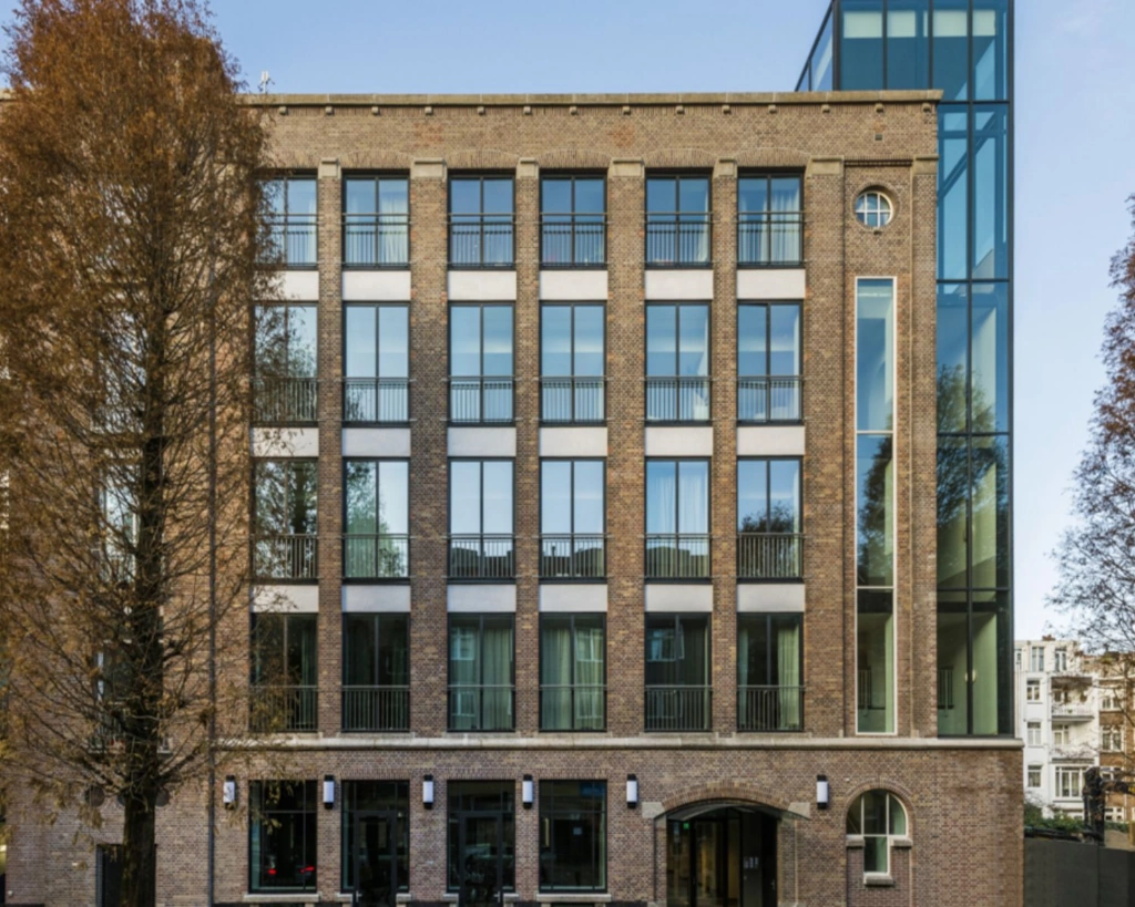 Vooraanzicht van een modern kantoorgebouw met bakstenen gevel en grote ramen aan de Karel du Jardinstraat 1 in Amsterdam.