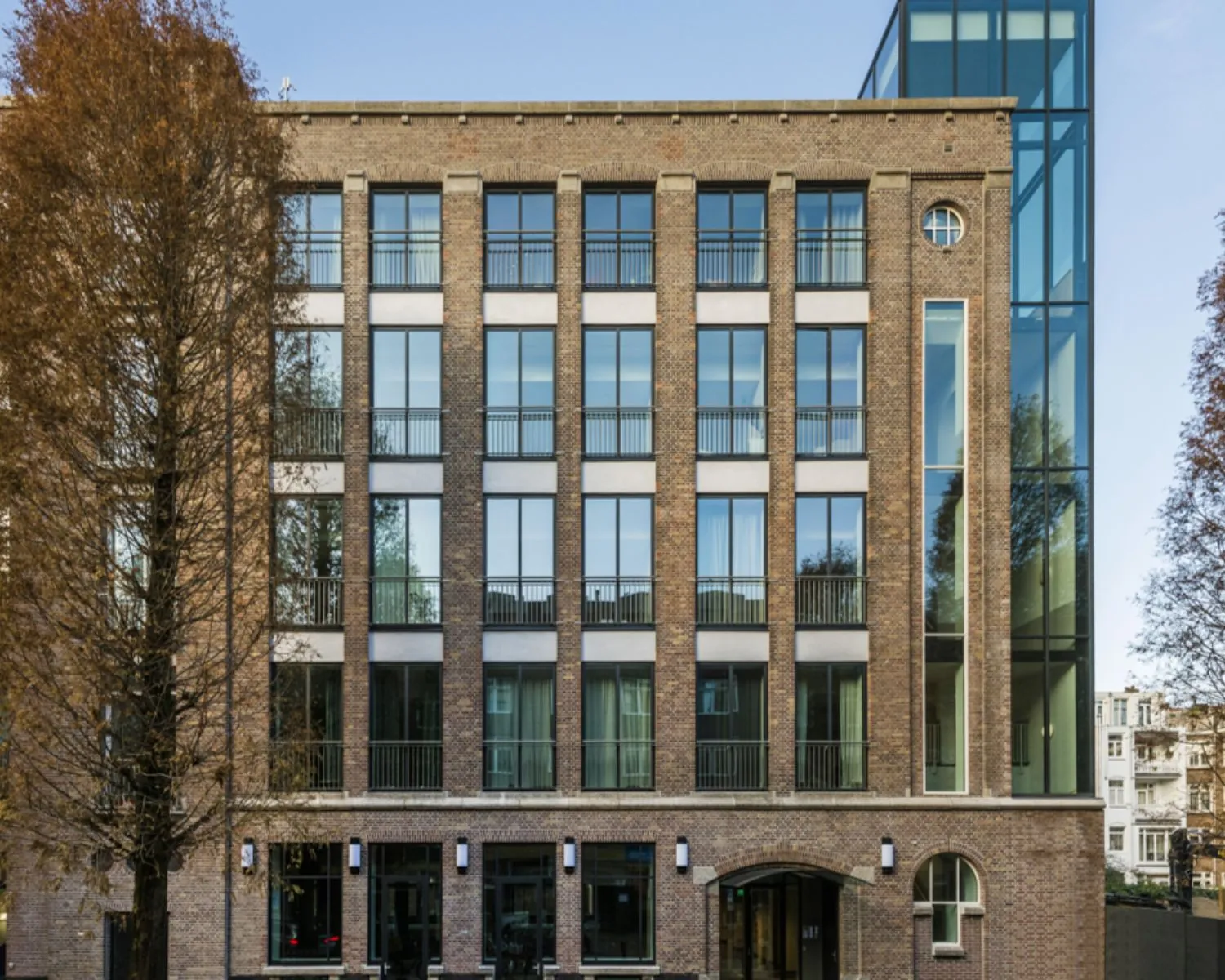 Vooraanzicht van een modern kantoorgebouw met bakstenen gevel en grote ramen aan de Karel du Jardinstraat 1 in Amsterdam.