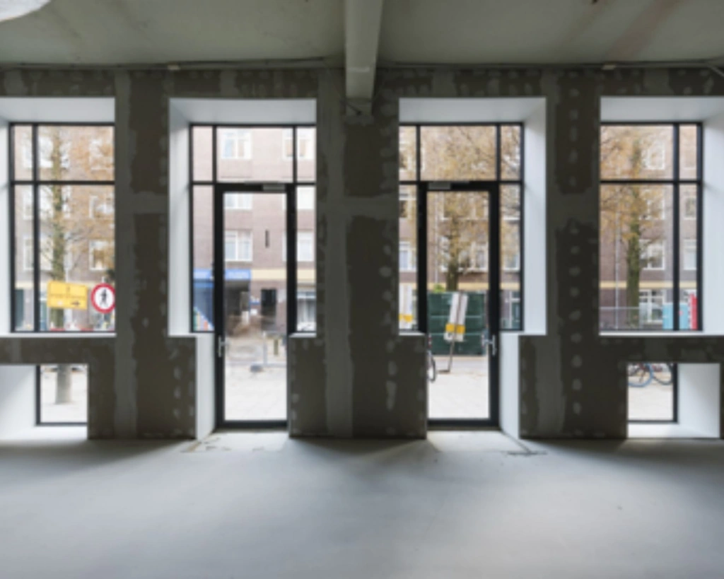 Lege kantoorruimte in aanbouw met grote ramen aan de Karel du Jardinstraat in Amsterdam.