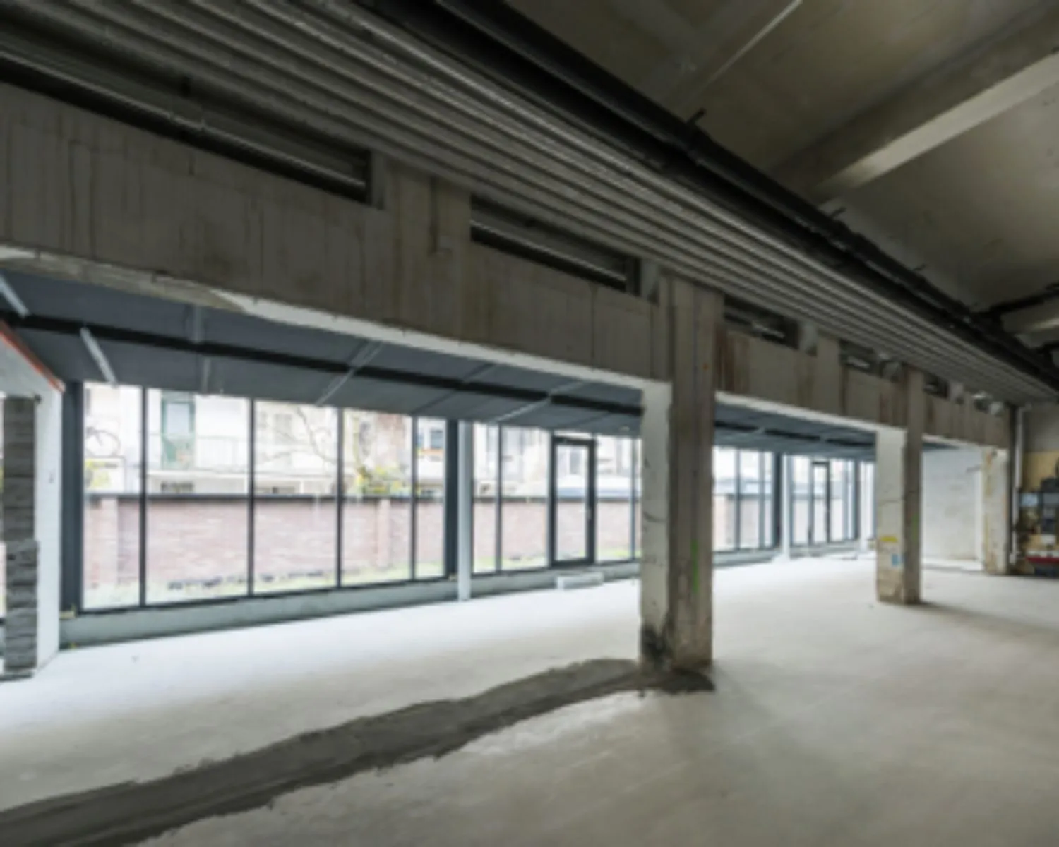 Leegstaande, industriële kantoorruimte met grote ramen aan de Karel du Jardinstraat in Amsterdam.