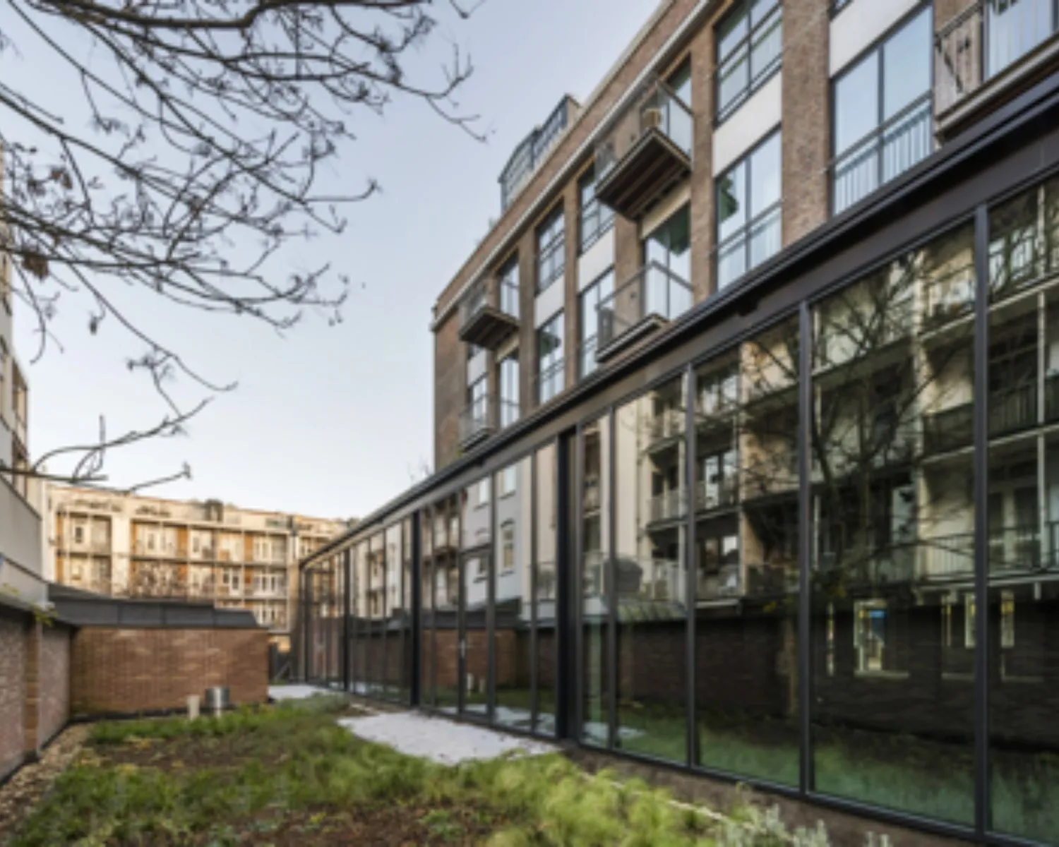 Moderne kantoorruimte met grote glazen gevel in een binnentuin aan de Karel du Jardinstraat in Amsterdam.