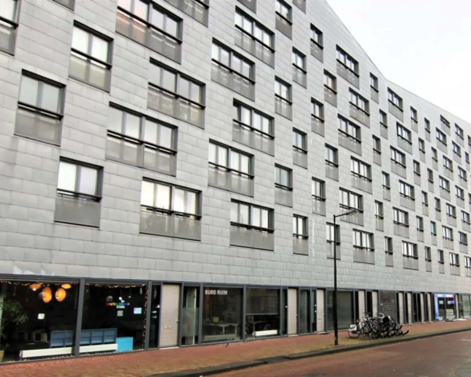 Moderne kantoorruimte aan de Baron G.A. Tindalstraat met grote ramen en een fietsenrek voor de ingang.