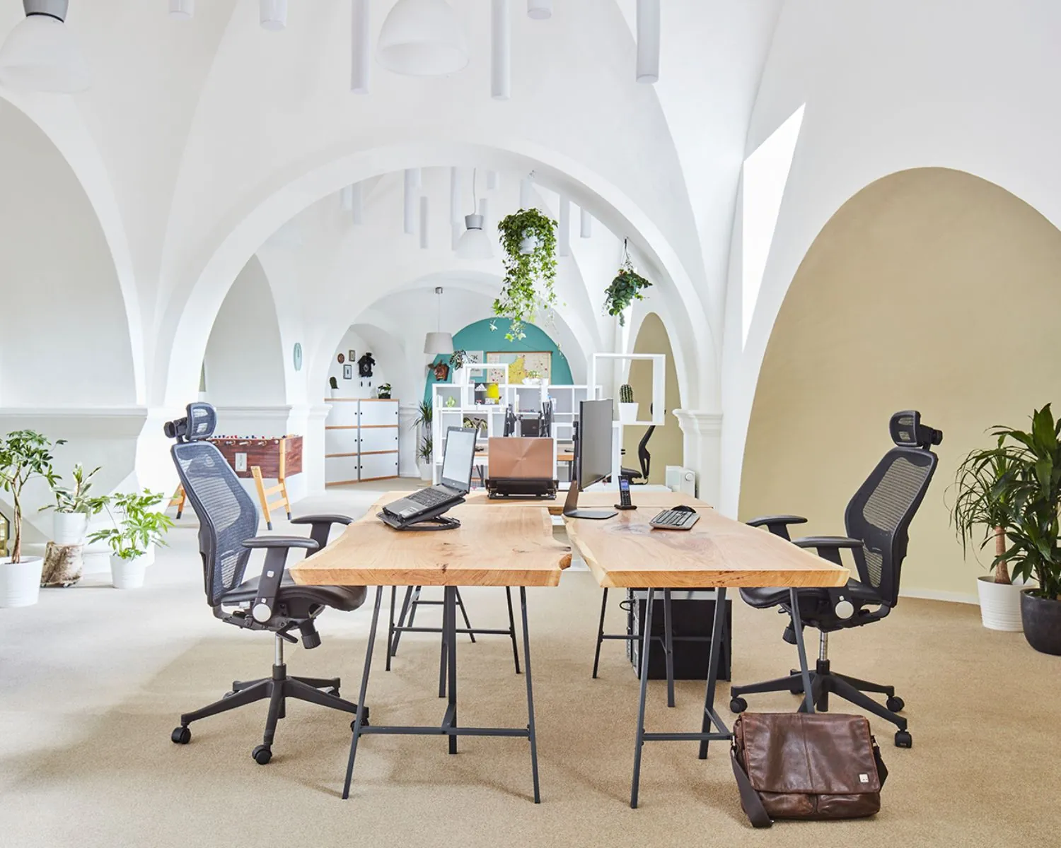 Moderne kantoorruimte met hoge witte gewelven, houten bureaus, ergonomische stoelen en veel planten aan de Batjanstraat 11 in Amsterdam.