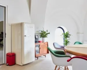 Licht en modern ingericht kantoorinterieur aan de Batjanstraat 11 in Amsterdam met retro koelkast, ronde vergadertafel en kleurrijke stoelen.