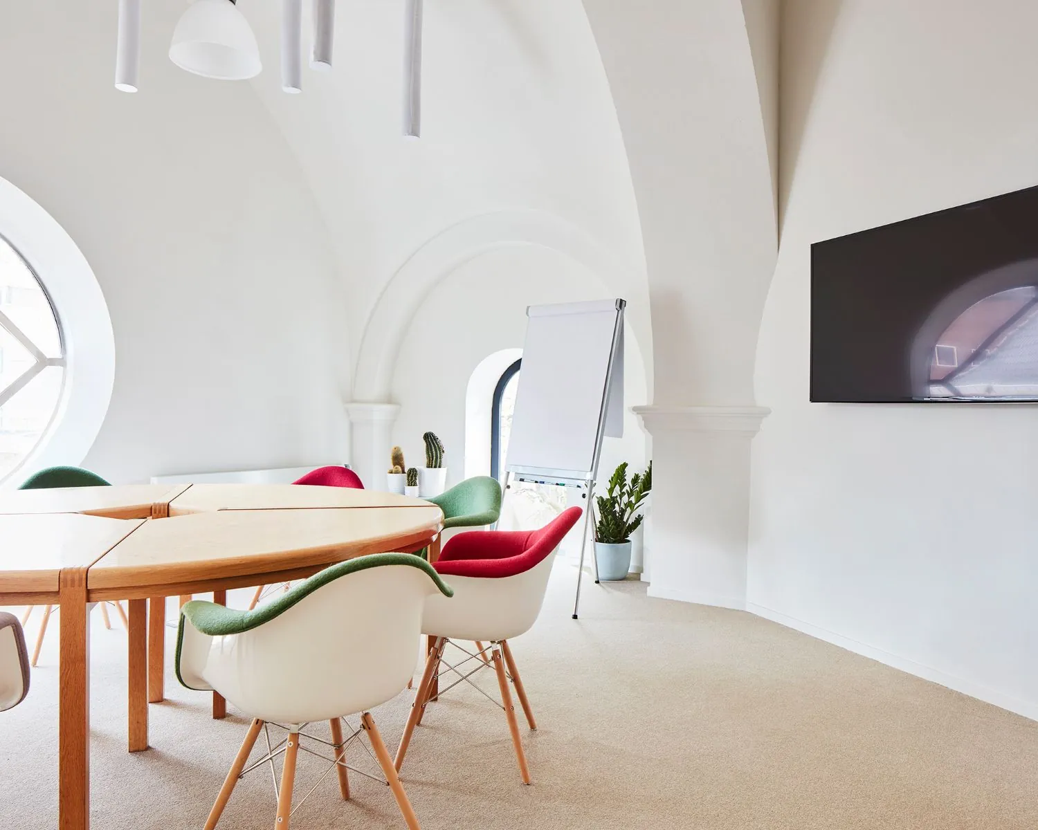 Moderne en lichte vergaderruimte met ronde houten tafel, kleurrijke stoelen, flatscreen en flipover in een kantoor aan de Batjanstraat 11 in Amsterdam.
