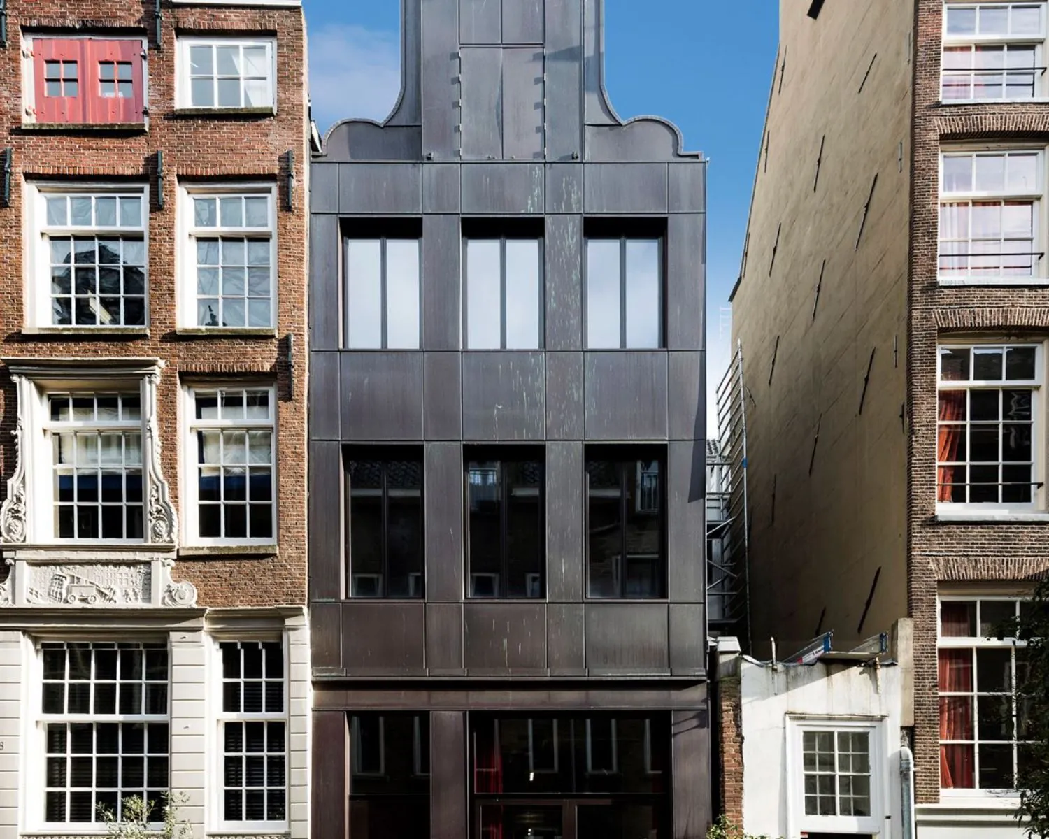 Voorgevel van een modern kantoorpand aan de Bergstraat 6 in Amsterdam, ingeklemd tussen twee historische gebouwen.