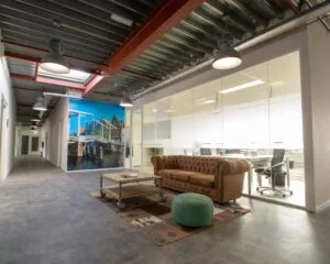 Modern ingerichte kantoorruimte aan de Bingerweg 18 met glazen vergaderruimte, industriële details en een loungehoek met leren bank.