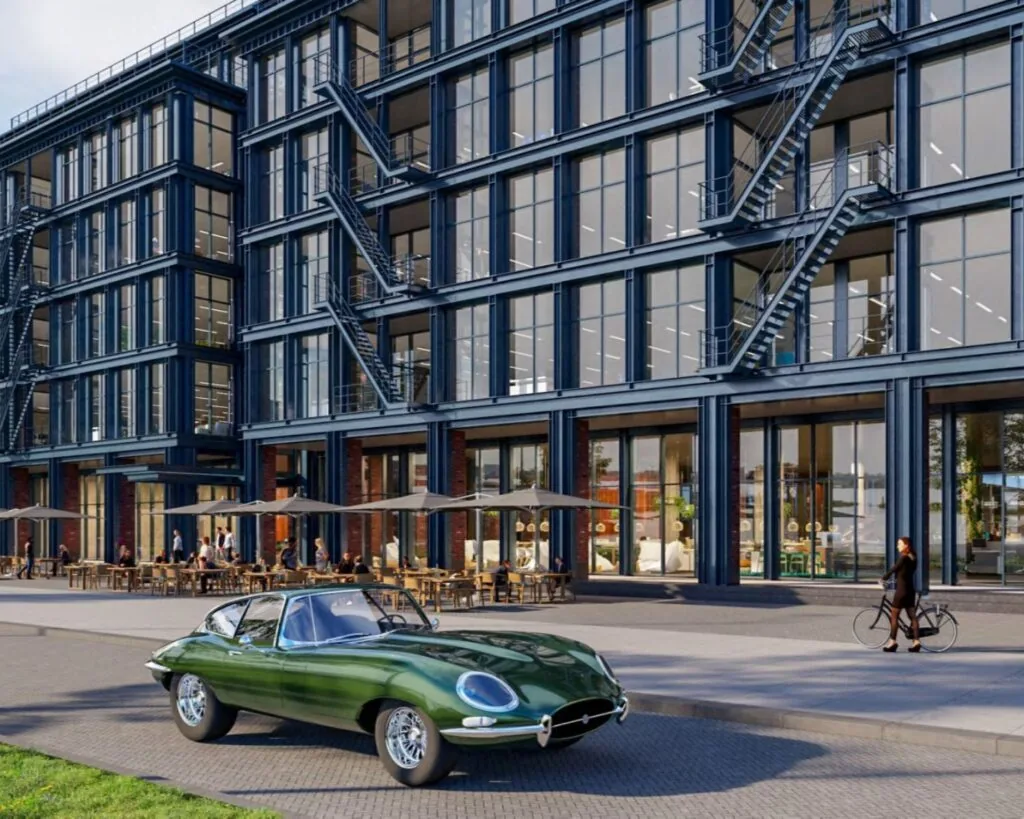 Moderne kantoorruimte aan de Danzigerkade 14-15 in Amsterdam met glazen gevel, terras en een klassieke groene auto op de voorgrond.