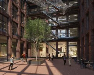 Moderne binnentuin van een kantoorpand aan de Danzigerkade 14-15 in Amsterdam met bakstenen gevels, een grote boom, en mensen op het terras.