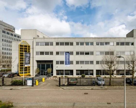 Vooraanzicht van een modern kantoorgebouw aan de Diemermere 1 in Diemen, met parkeerplaatsen en opvallende gele entree.