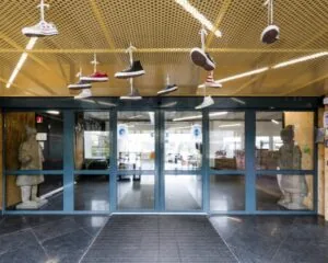 Entree van kantoorpand Diemermere 1 in Diemen met hangende sneakers aan het plafond en twee beelden bij de schuifdeuren.