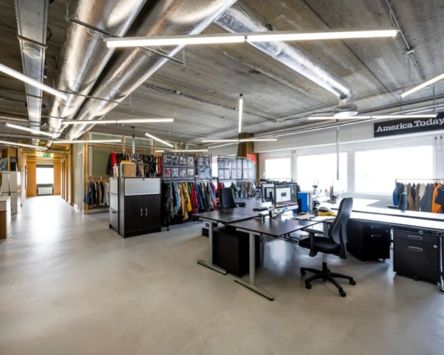 Moderne kantoorruimte in Diemermeren 1 in Diemen met werkplekken, kledingrekken en industrieel plafond.