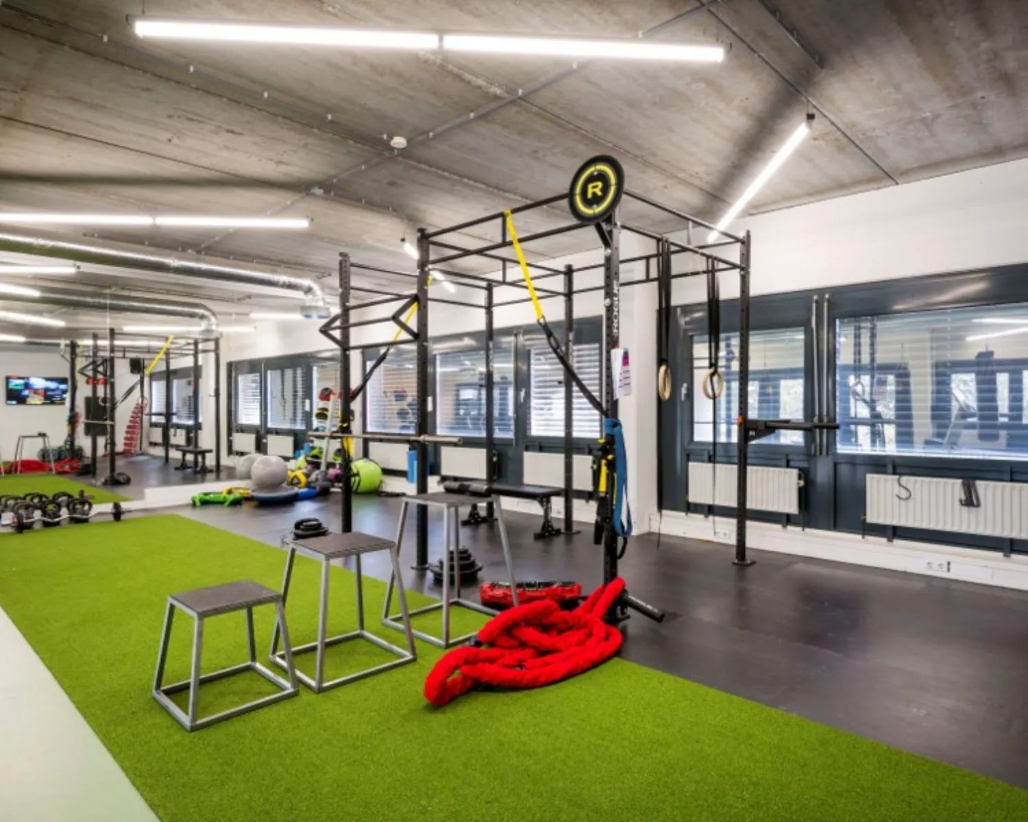 Moderne fitnessruimte met kunstgrasvloer en diverse trainingsapparaten in kantoorpand Diemermere 1 in Diemen.