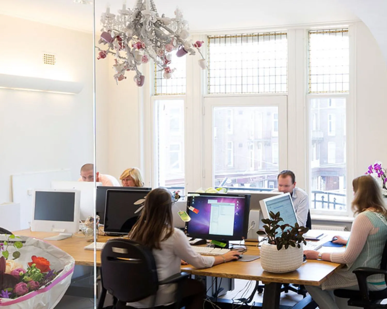 Moderne kantoorruimte aan de Emmalaan 25 in Amsterdam met mensen werkend achter computers aan een grote houten tafel.