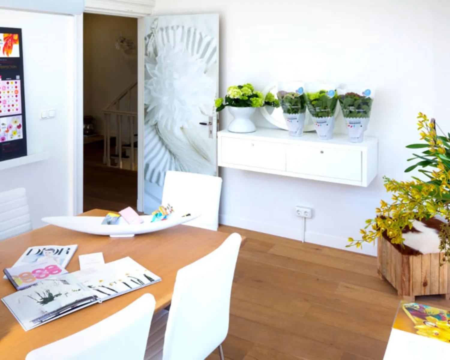 Moderne kantoorruimte aan de Emmalaan 25 in Amsterdam met houten vloer, witte meubels en kleurrijke bloemendecoratie.