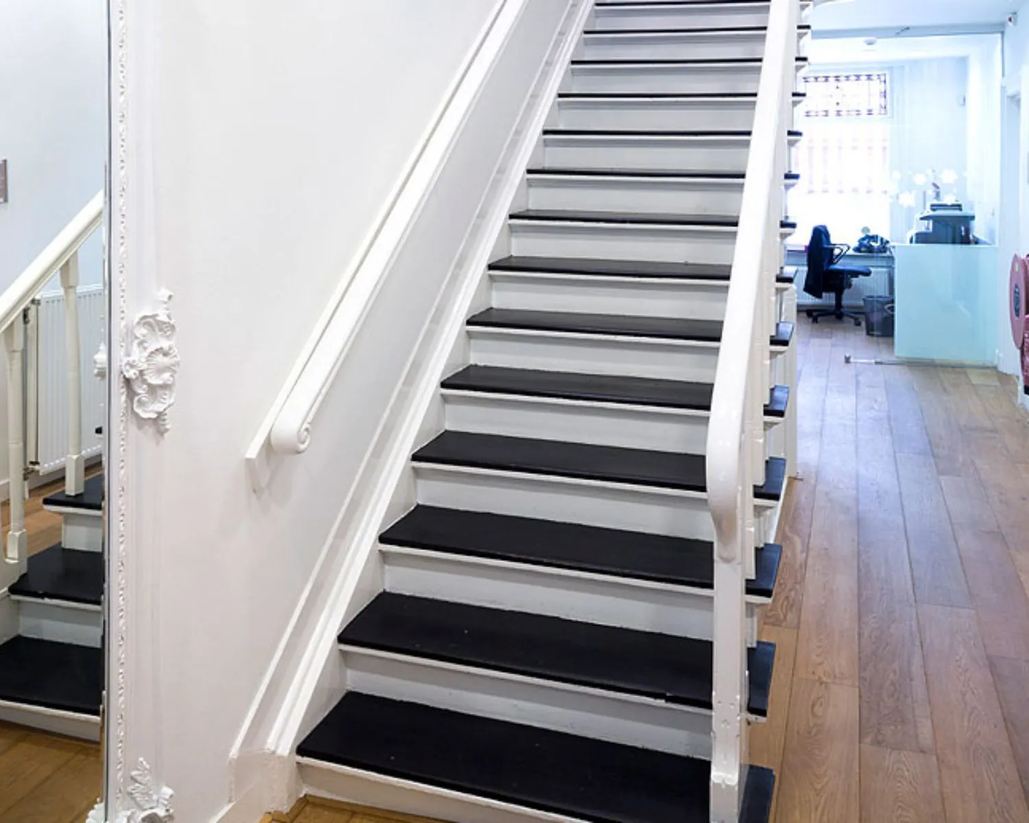 Trapopgang met zwarte treden en witte leuningen in een kantoorruimte aan de Emmalaan 25 in Amsterdam.